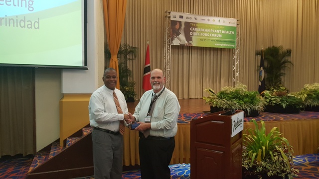 Dennis Martin (r), an official of the United States Department of Agriculture presents Eric Evelyn, with an award by the department at a recent meeting in Trinidad, for his contribution to the Caribbean Plant Health Directors Forum